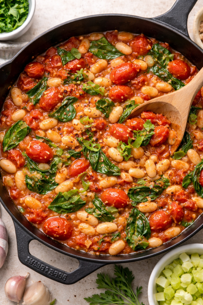 tomato white bean skillet with cannellini beans, tomatoes, and spinach in a cast iron pan
