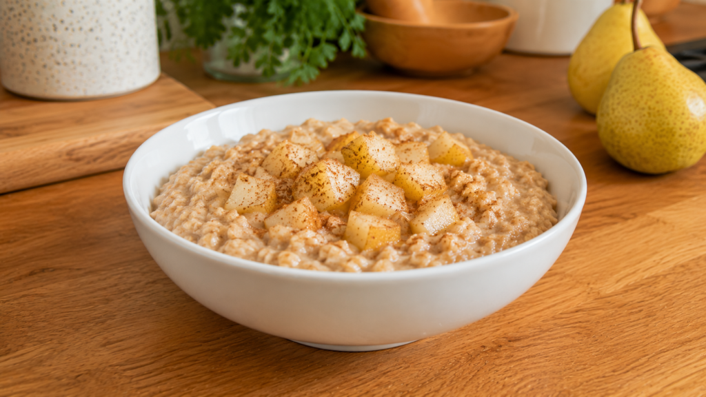 Cinnamon pear oat bowl topped with diced pears and a sprinkle of cinnamon in a white bowl on a wooden countertop.
